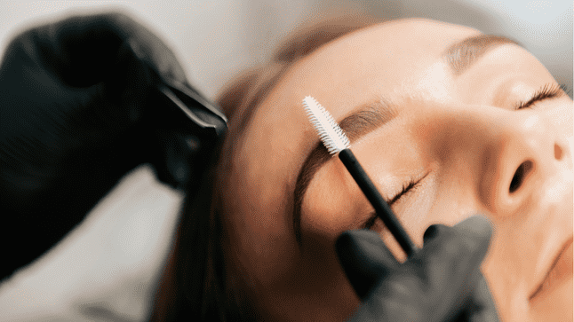 Woman getting her eyebrows brushed with a spoolie