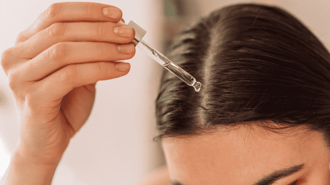 Woman applying hair oil to her scalp