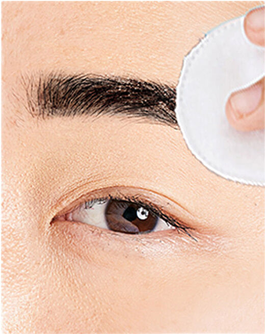 woman wiping eyebrow tint off her eyebrows