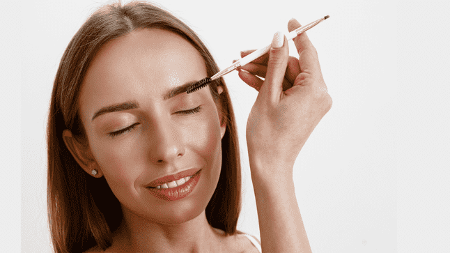 woman brushing her dark eyebrows