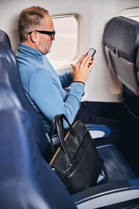 man sitting on plane scrolling on phone