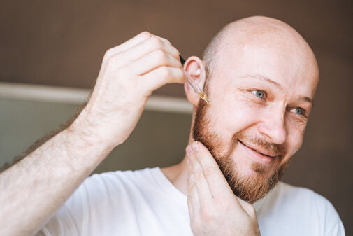 man applying beard growth oil
