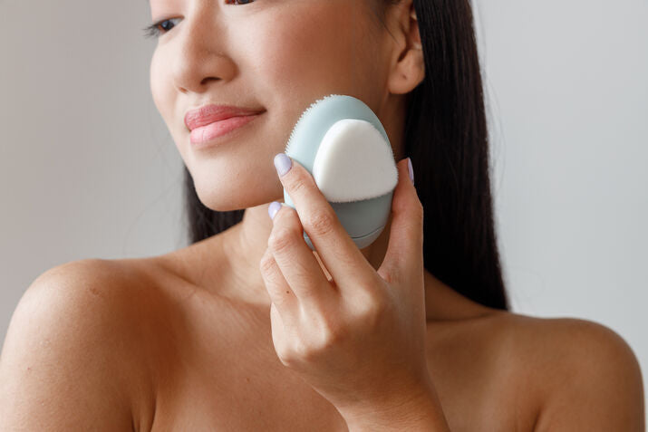 Woman cleansing face with skin care tool