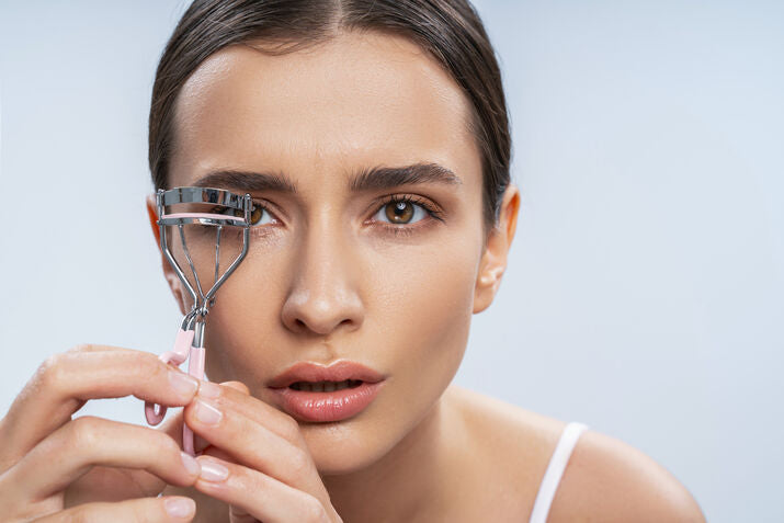 Woman using eyelash curler