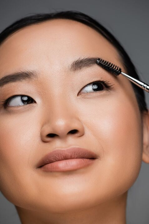 Close up of Asian woman brushing her brows