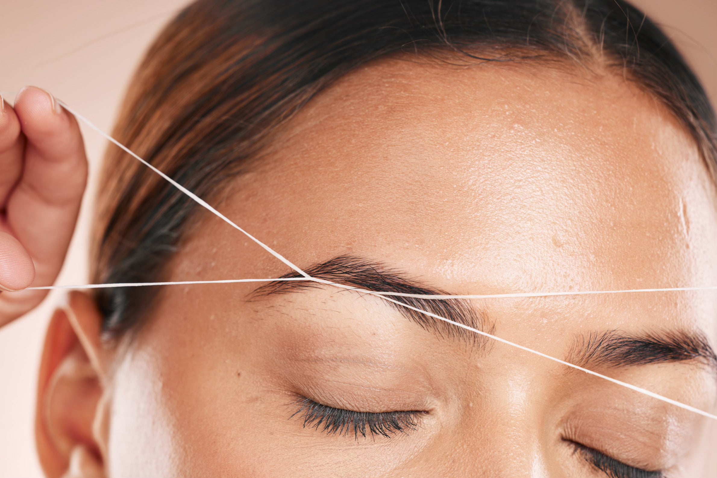 Woman threading her eyebrows