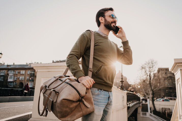 man walking and taking a call with large bag