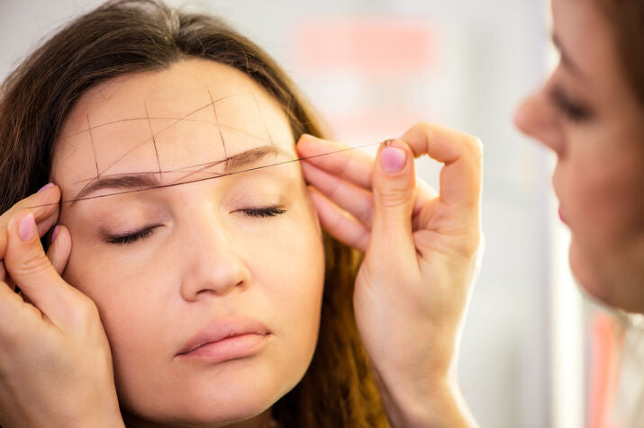 woman having her eyebrows mapped out