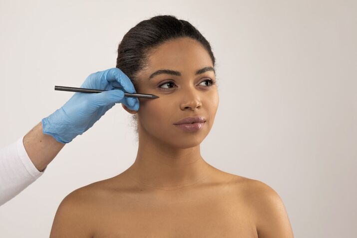plastic surgeon mapping out young woman's face
