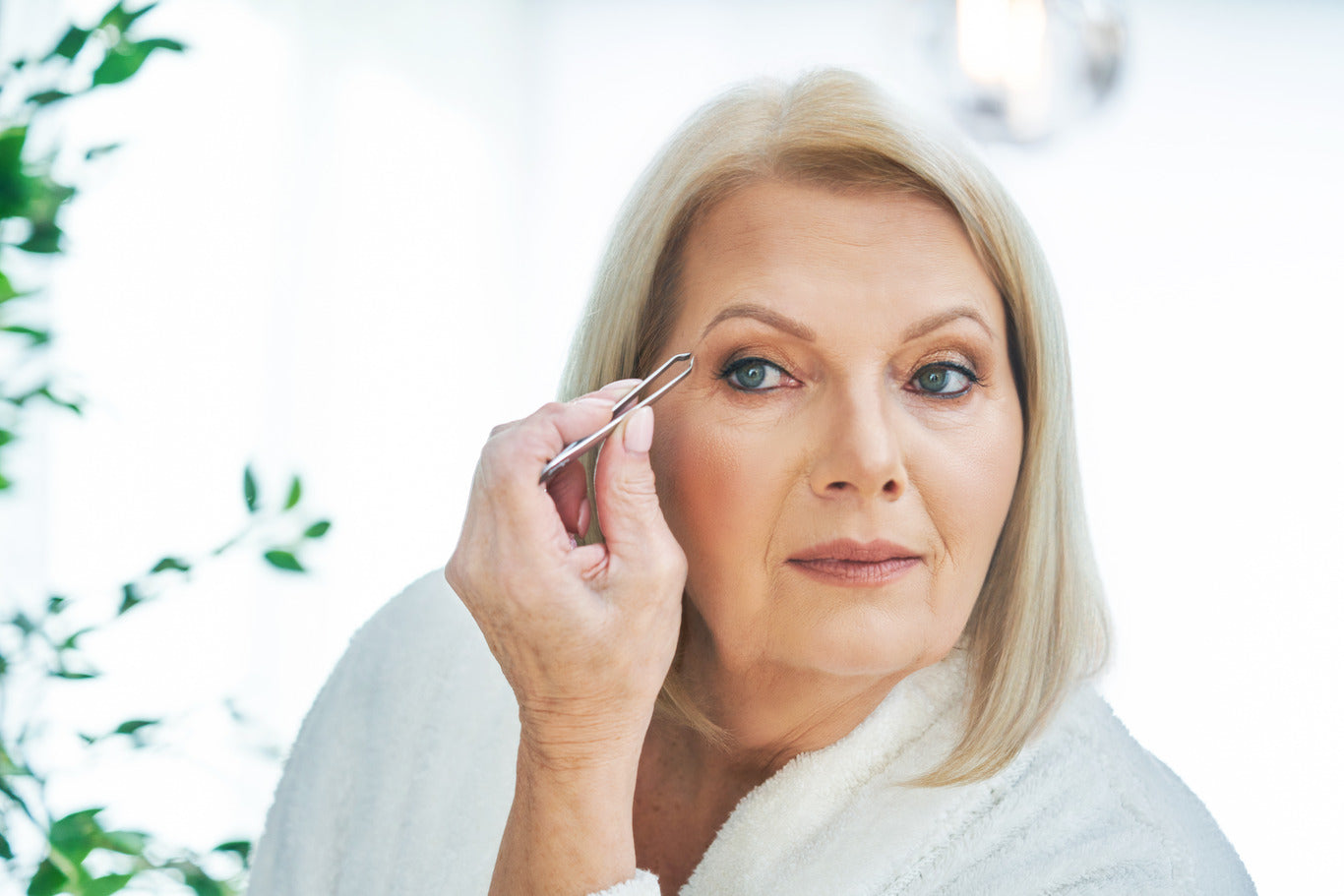 Older woman tweezing her brows