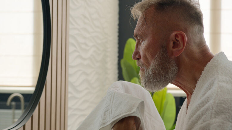 aged man with a gray beard looking in the mirror