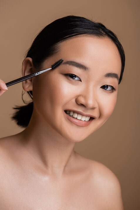 Beautiful woman brushing brows smiling