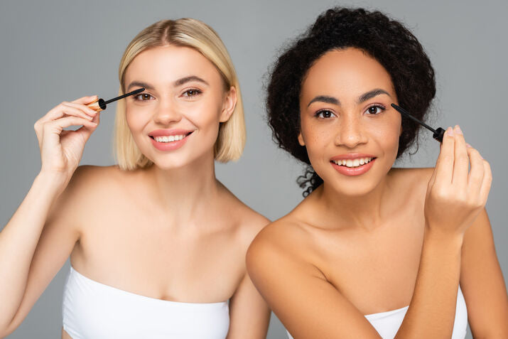two woman applying mascara