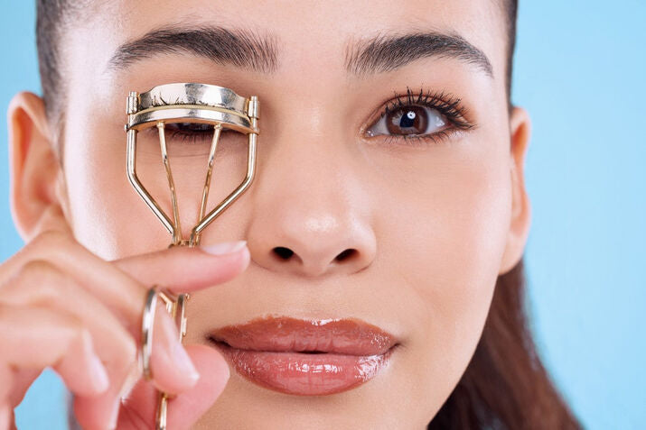 women using eyelash curler on her tinted lashes