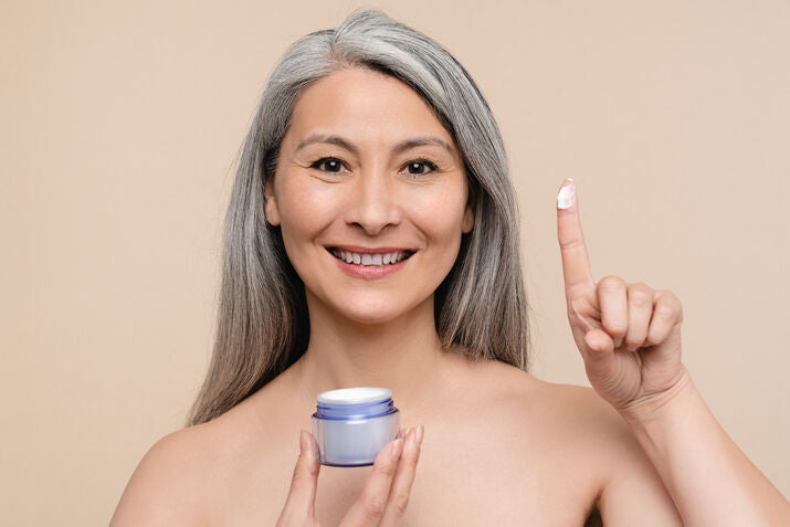 Older woman holding cream product on her finger