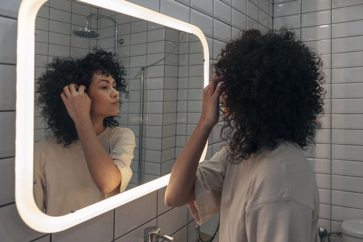 Woman looking at herself in light up mirror
