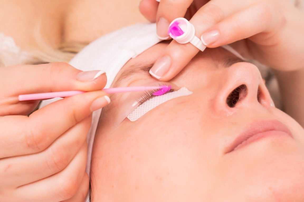 woman applying eyelash lift gel at salon