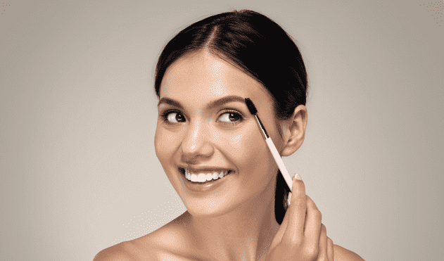 Beautiful woman brushing her brows 