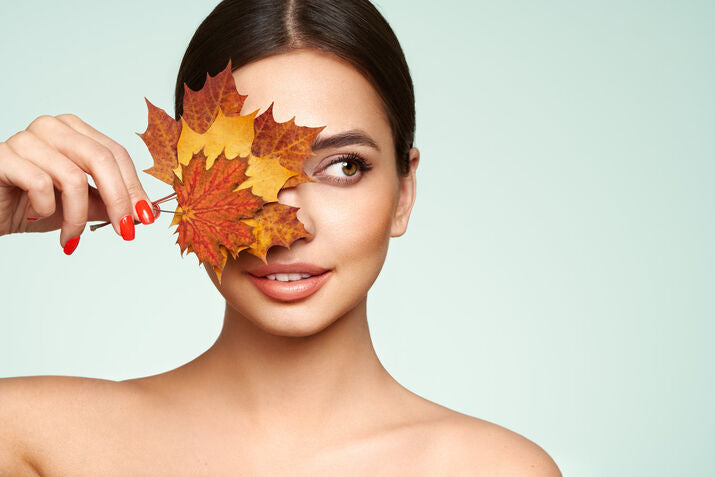 Women smiling and covering face with autumn leave