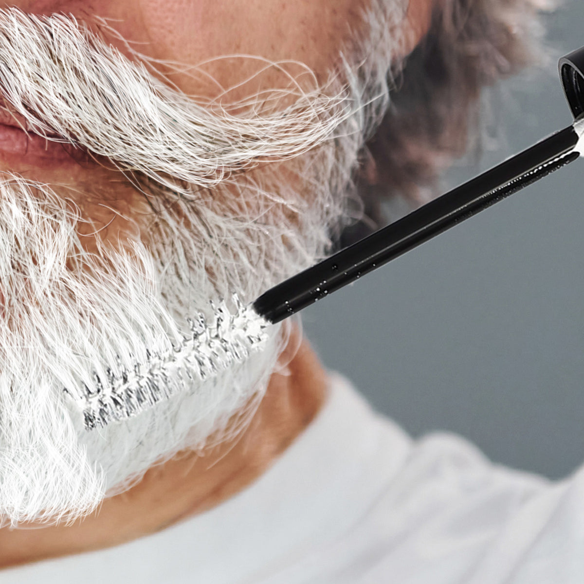 senior man applying white beard dye to his grey beard
