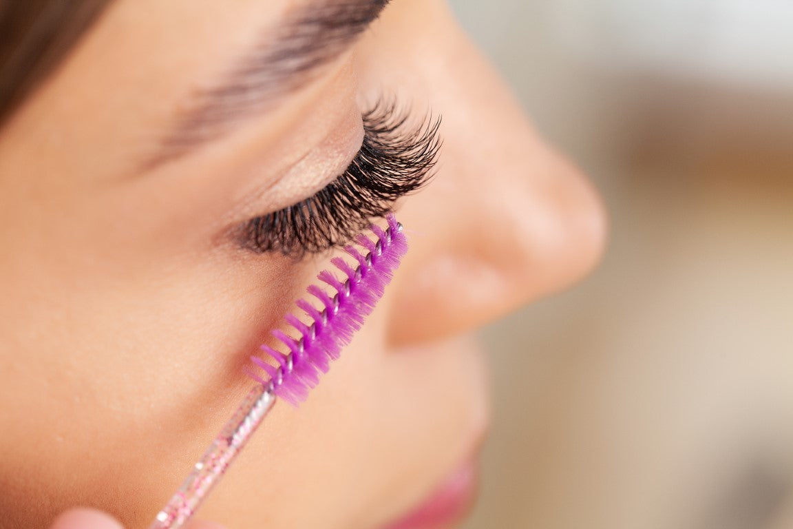 women brushing her tinted lashes with a spoolie