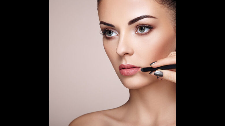 Woman applying pink lipstick 