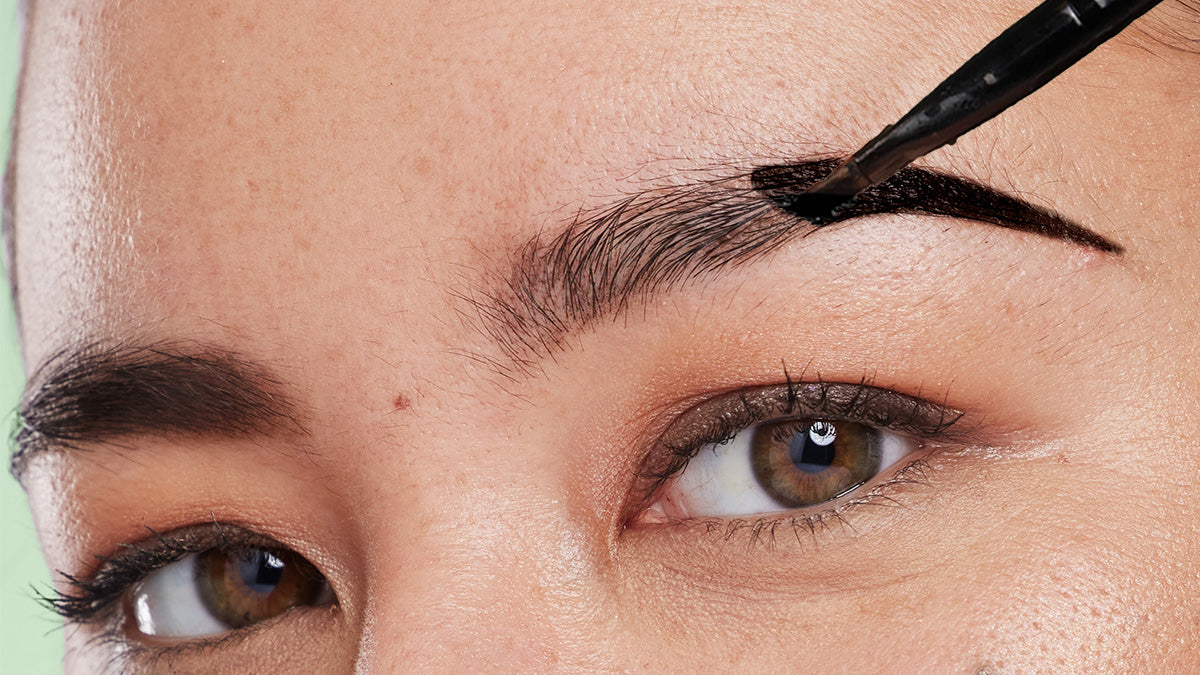 Woman tinting her brows dark brown with brush