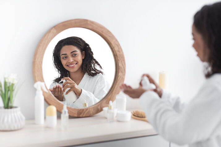 woman smiling at mirror applying lotion