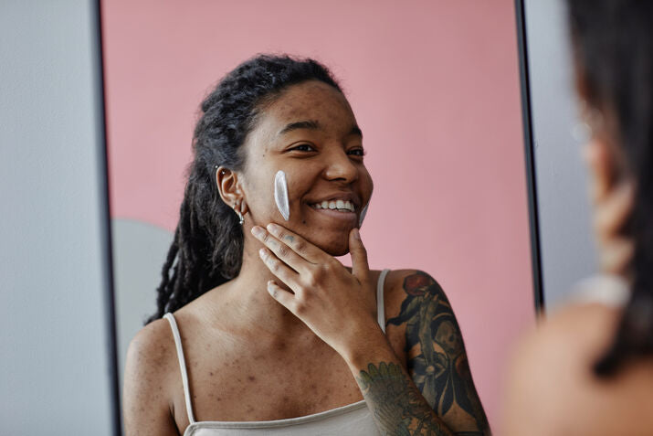 Woman smiling and holding jar of skincare