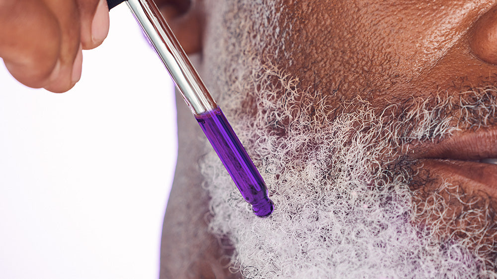 Closeup senior man applying purple serum to beard