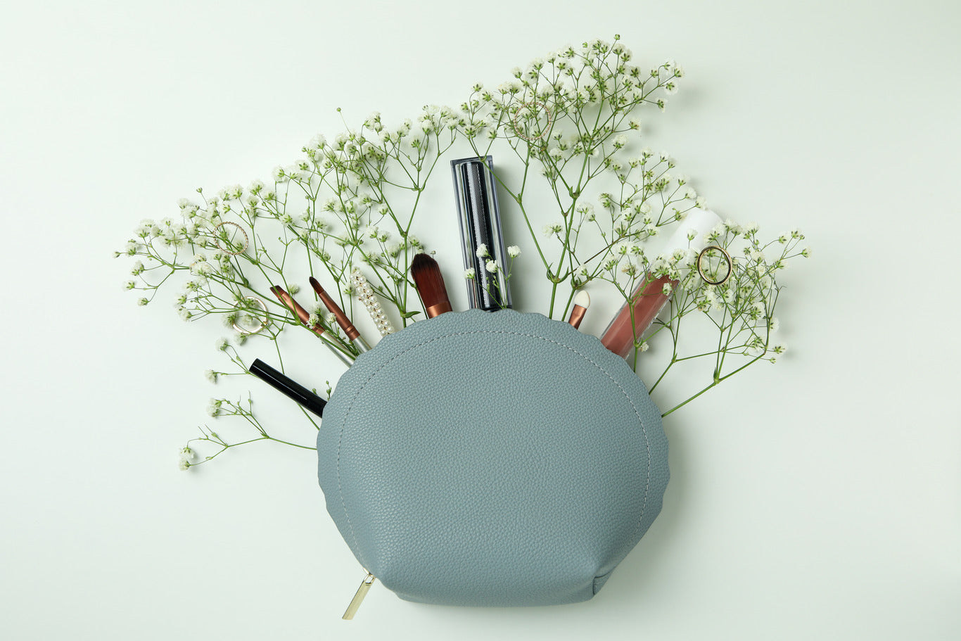 small blue makeup bag with white flowers and makeup brushes