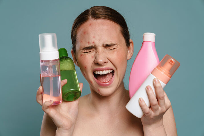 woman with acne screaming holding products