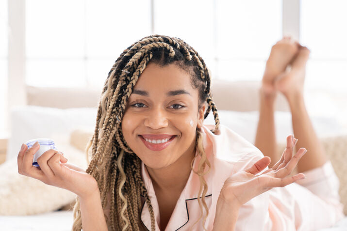 Woman smiling and holding jar of skincare