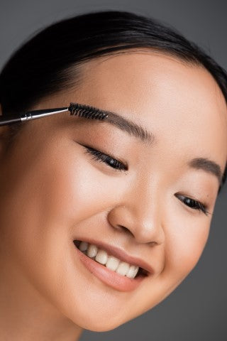 Beautiful woman brushing her brows