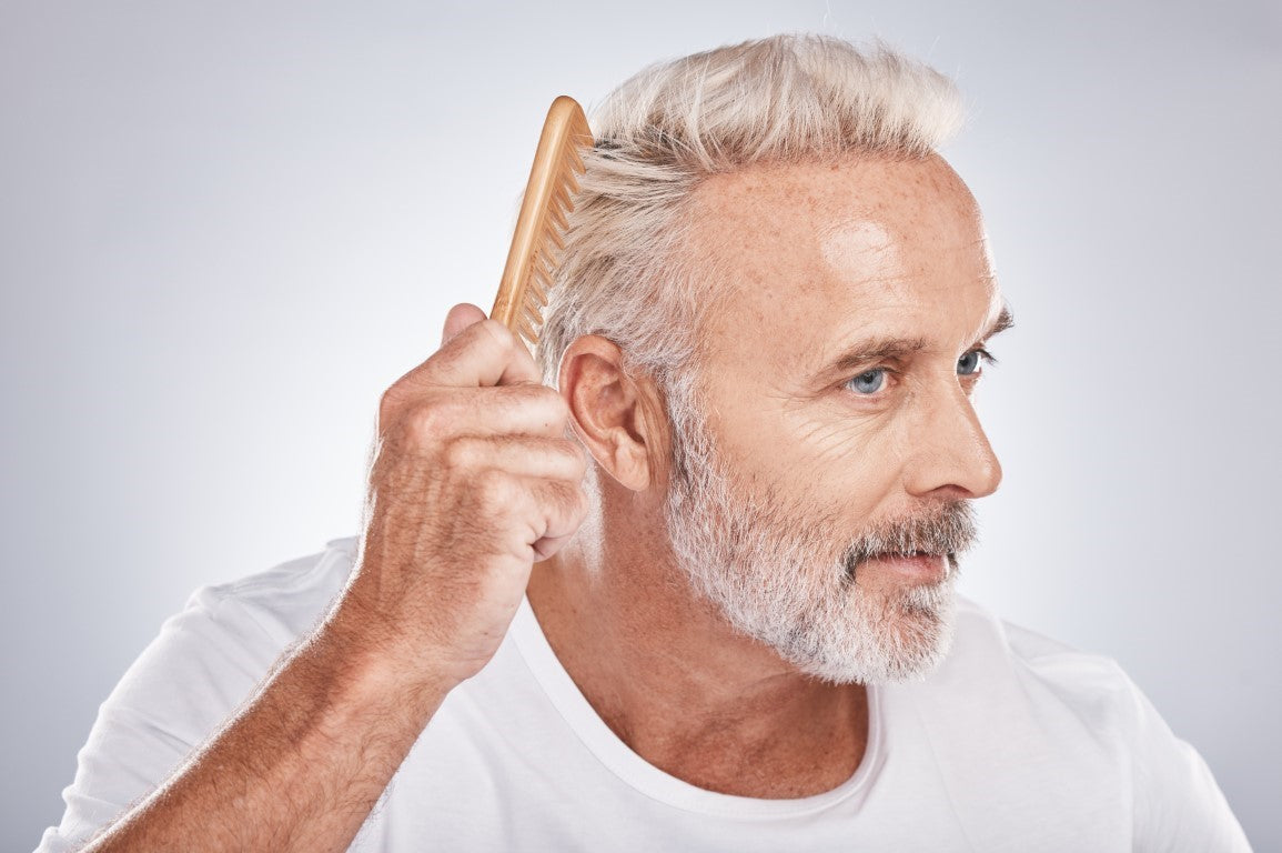 Older man combing through his grey hair. 