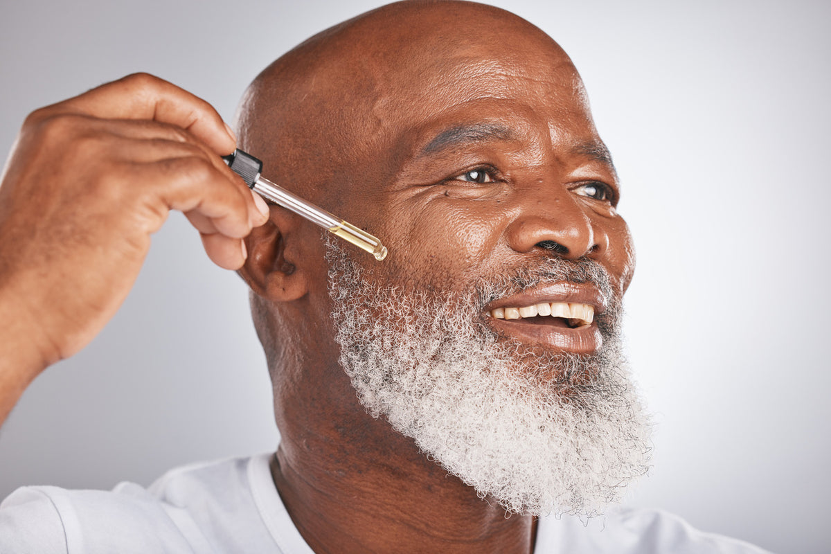man applying growth serum to his gray beard