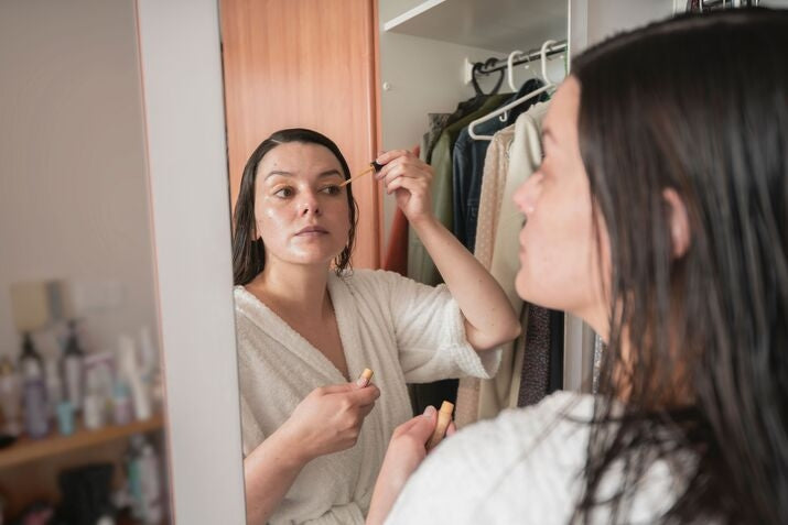 woman in robe applying makeup