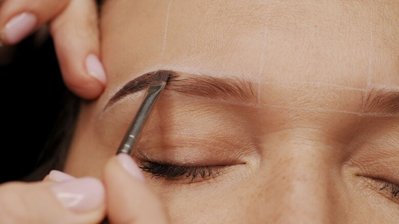 Person applying eyebrow tint with a thin brush on eyebrows close up